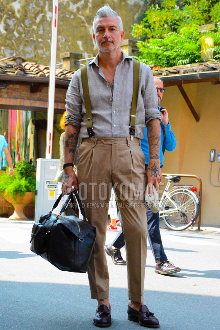 Spring, summer, and fall men's coordinate outfit with plain gray shirt, plain olive green suspenders, plain brown slacks, brown tassel loafer leather shoes, and plain black Boston bag.