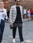 A men's spring/summer/fall outfit for men with plain black sunglasses, beige checked tailored jacket, plain black t-shirt, plain black slacks, white low-cut sneakers, and plain black clutch bag/second bag/drawstring.