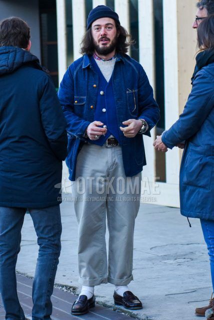Fall and winter men's coordinate outfit with solid navy knit cap, solid blue denim jacket, solid blue gilet, solid gray sweater, checked shirt, solid leather belt, solid gray chinos, solid white socks, and black coin loafer leather shoes.