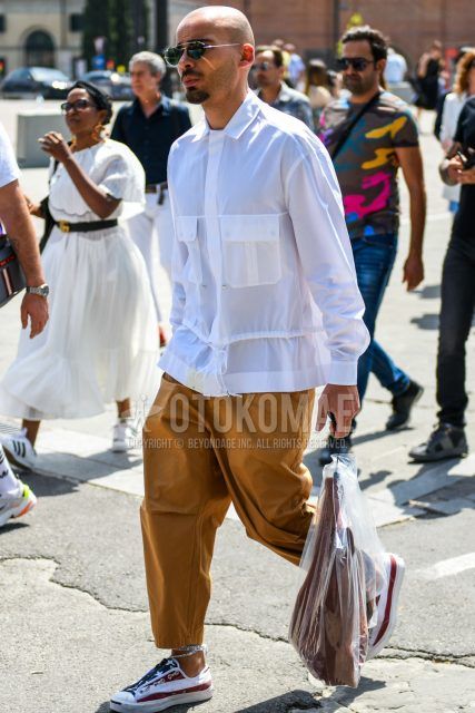 Spring, summer and fall men's coordinate outfit with plain silver sunglasses, plain white shirt, plain brown cotton pants and multi-colored low-cut sneakers.