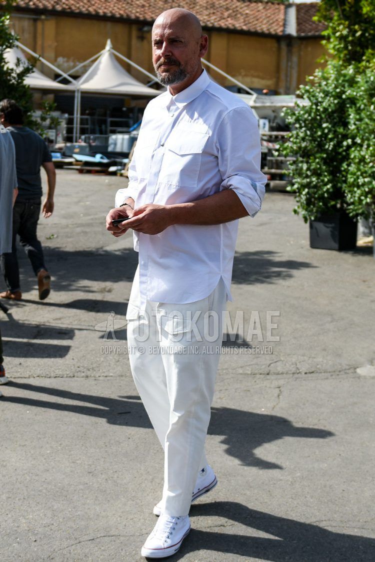 A men's spring/summer/fall coordinate outfit with a plain white shirt, plain white cotton pants, and white high-cut Converse sneakers.