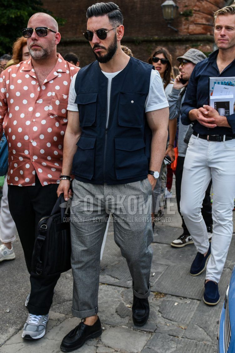 Spring and fall men's outfit with plain sunglasses, plain navy gilet, plain white t-shirt, plain wool gray other, black other leather shoes, and plain black briefcase/handbag.