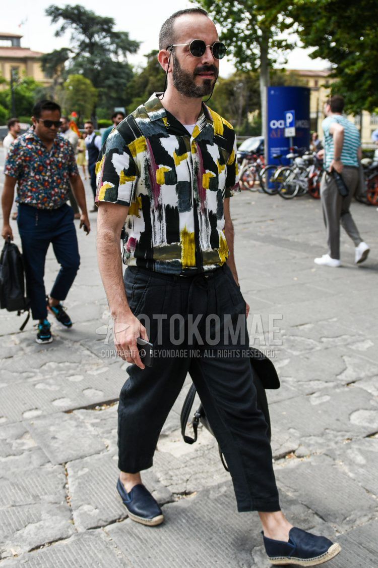 Summer men's coordinate outfit with plain silver/black sunglasses, short sleeve open collar multi-colored and other shirts, plain black slacks, plain cropped pants, and plain black/navy espadrilles.