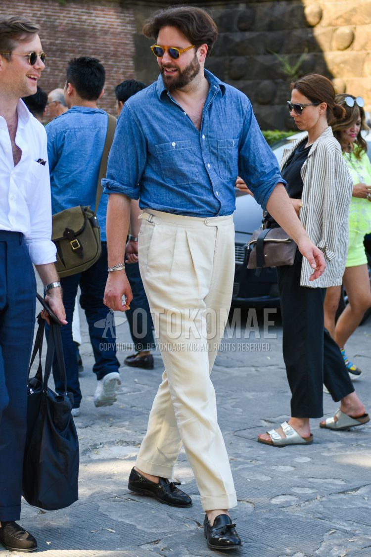 Spring/summer/fall men's coordinate outfit with solid orange sunglasses, solid blue denim/chambray shirt, solid beige beltless pants, and black tassel loafer leather shoes.