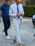Spring, fall and summer men's coordinate outfit with plain black glasses, plain white shirt, gray low-cut sneakers, light blue striped suit and blue dot tie.