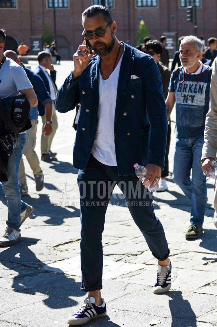 Spring, fall and summer men's coordinate outfit with plain black sunglasses, plain navy tailored jacket, plain white t-shirt, plain navy cotton pants and Adidas purple low-cut sneakers.
