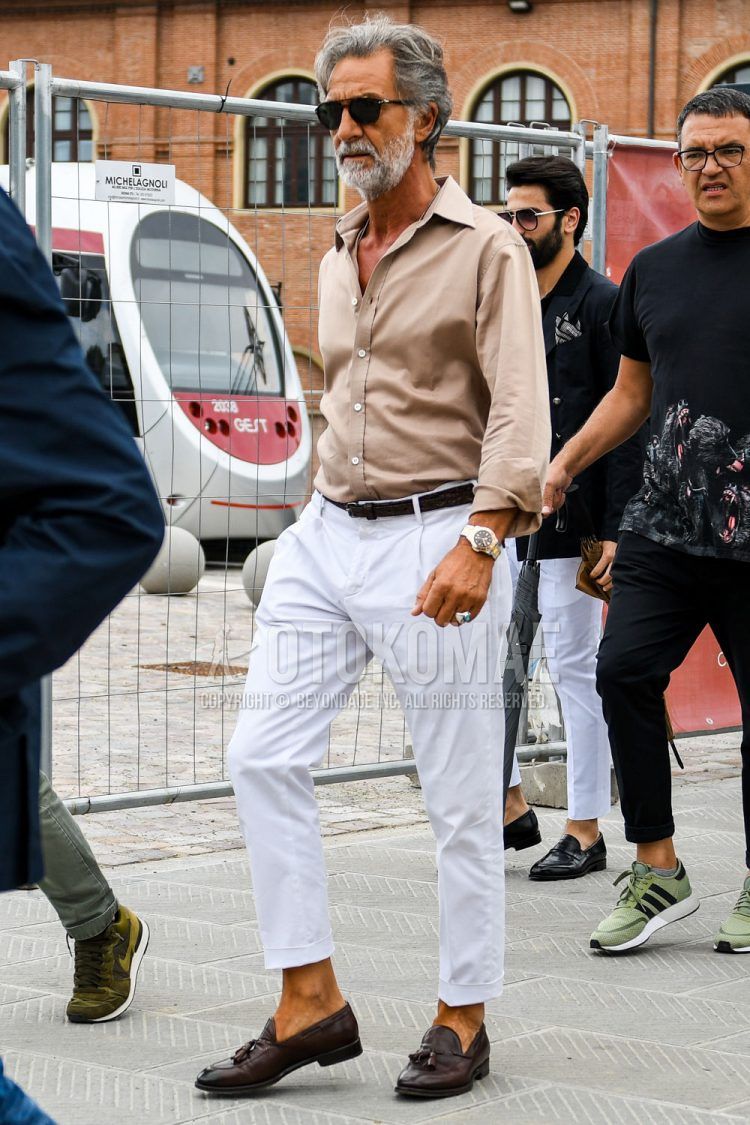 A summer/spring men's coordinate outfit with solid color sunglasses, solid color beige shirt, solid color brown leather belt, solid color white pleated pants, and solid color cropped pants.