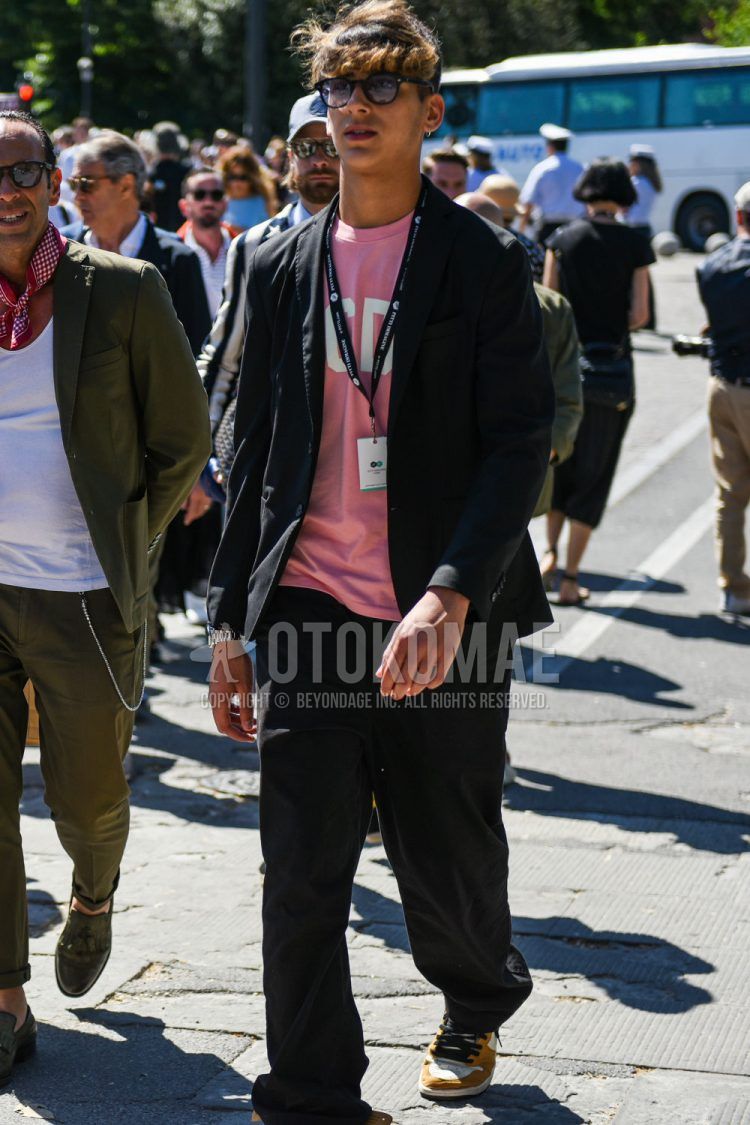 A men's spring, summer, and fall outfit of plain black sunglasses, a pink graphic t-shirt, and a plain black suit.