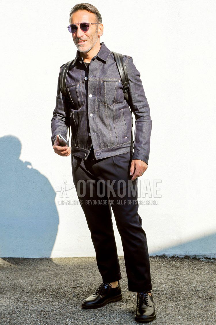 A spring and fall men's coordinate outfit with solid color sunglasses, solid color navy denim jacket, solid color black t-shirt, solid color black slacks, and black plain toe leather shoes.