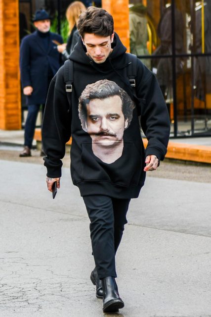 A black graphic hoodie, plain gray slacks, and black side gore boots are worn with a men's oversized fall/winter outfit.