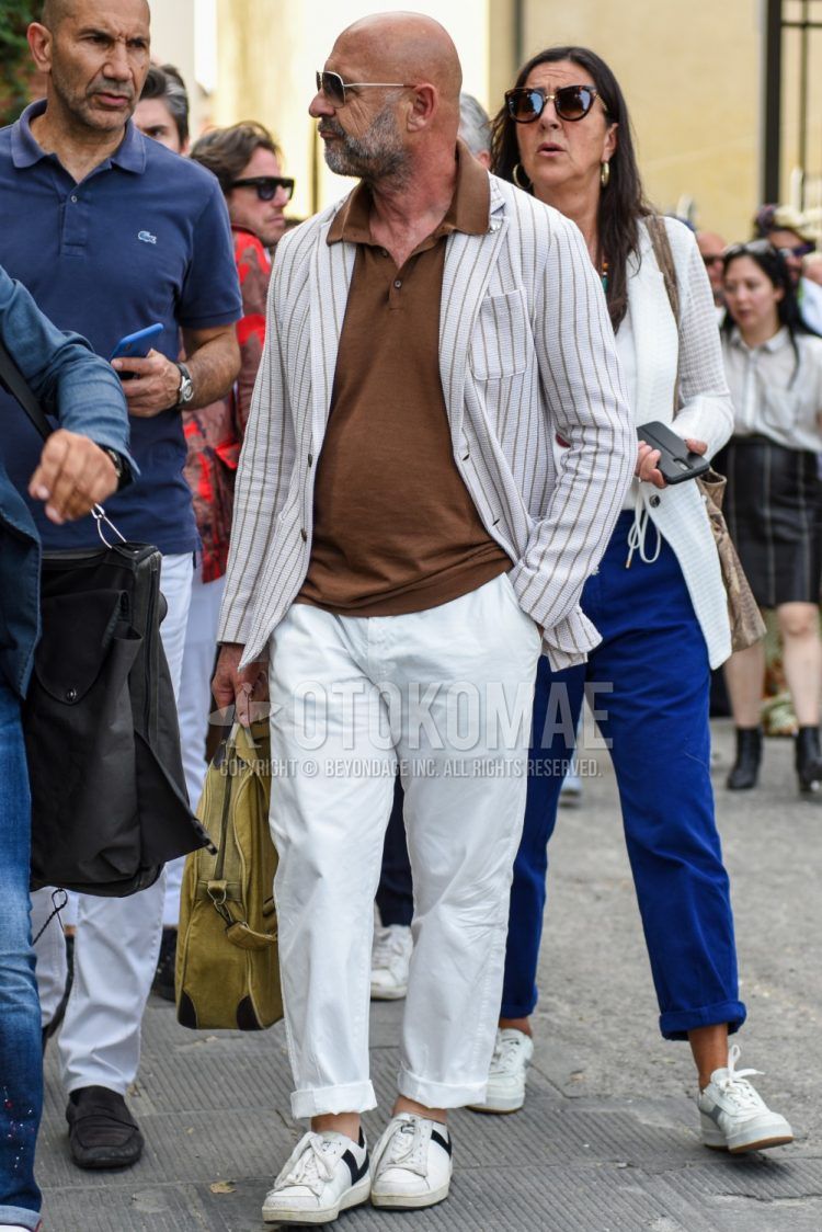 Spring, summer and fall men's coordinate outfit with plain silver sunglasses, white striped tailored jacket, plain brown polo shirt, plain white cotton pants and white low-cut sneakers.
