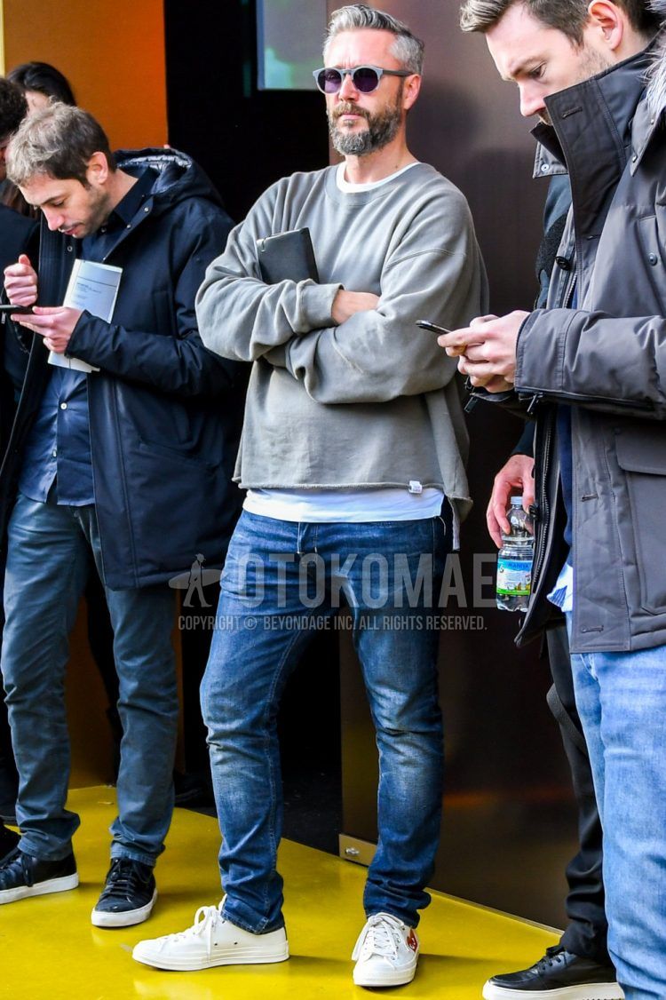 Spring and fall men's coordinate outfit with plain sunglasses, plain gray sweatshirt, plain white t-shirt, plain blue denim/jeans, and white low-cut sneakers by Comme des Garcons Play Converse.