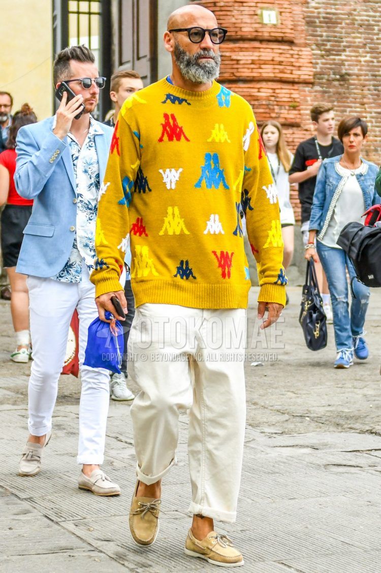 Spring/summer/fall men's coordinate outfit with plain black sunglasses, yellow other sweater, plain light blue t-shirt, plain white denim/jeans, and beige moccasins/deck shoes leather shoes.