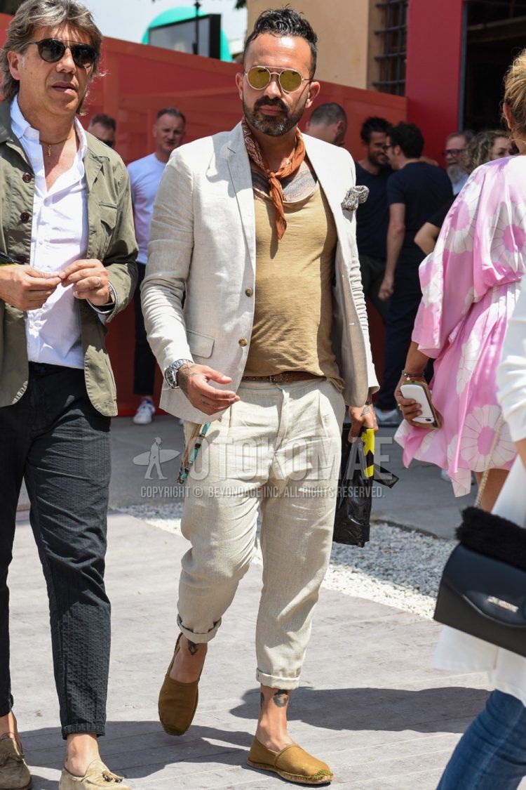 A spring/summer men's outfit with plain gold sunglasses, brown paisley bandana/neckerchief, plain white tailored jacket, plain beige t-shirt, plain brown leather belt, plain white slacks, and plain beige espadrilles.