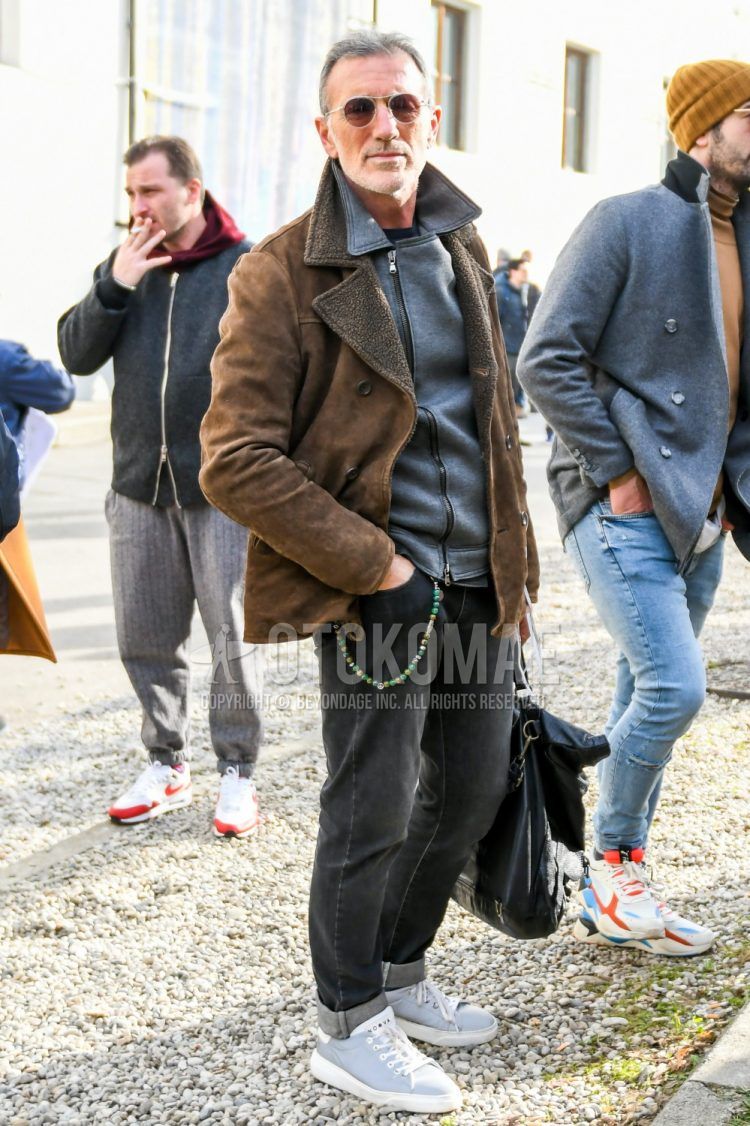 Winter menswear outfit with solid color sunglasses, solid color brown leather jacket (except riders), solid color black riders jacket, solid color gray denim/jeans, gray low cut sneakers, solid color black briefcase/handbag.