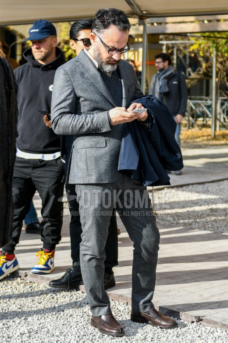 Fall and spring men's coordinate outfit with plain glasses, beige and other shirts, plain gray sweater, brown coin loafer leather shoes, and plain gray suit.