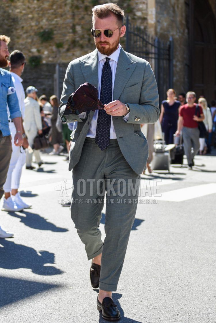 A spring and fall men's outfit with plain black sunglasses, plain white shirt, black tassel loafer leather shoes, plain gray suit, and navy or other tie.