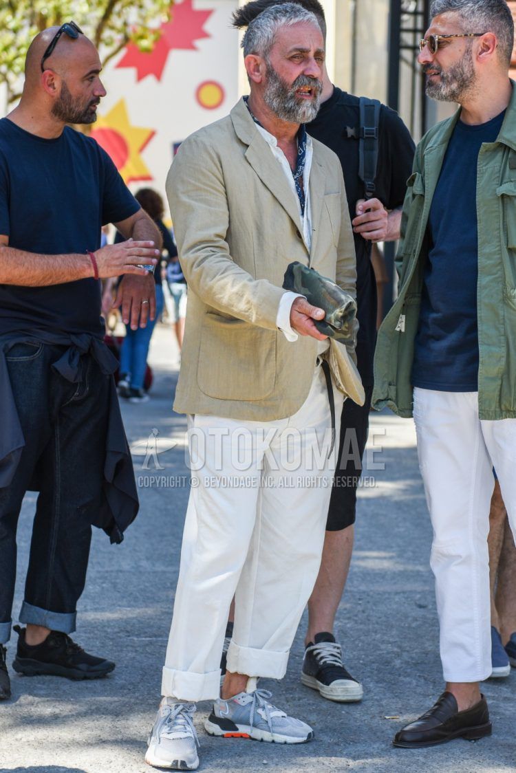 Spring, fall, and summer men's coordinate outfit with plain beige tailored jacket, plain white shirt, plain white cotton pants, and Adidas gray low-cut sneakers.