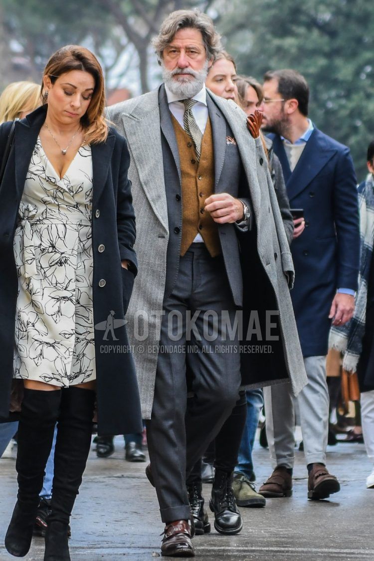Winter men's coordinate outfit with gray striped chester coat, plain brown gilet, plain white shirt, brown monk shoes leather shoes, plain gray suit, and beige striped tie.