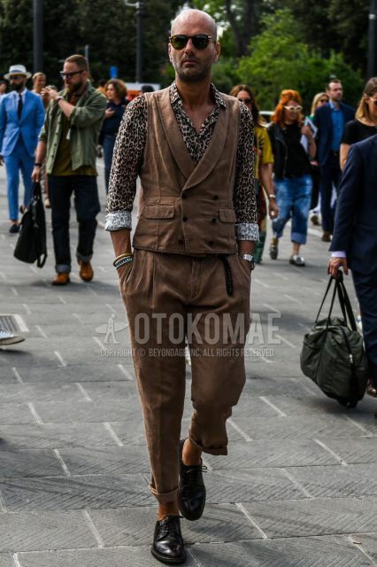 Spring, summer and fall men's coordinate outfit with brown tortoiseshell sunglasses, plain brown gilet, beige leopard shirt, plain brown slacks, plain pleated pants and black plain toe leather shoes.