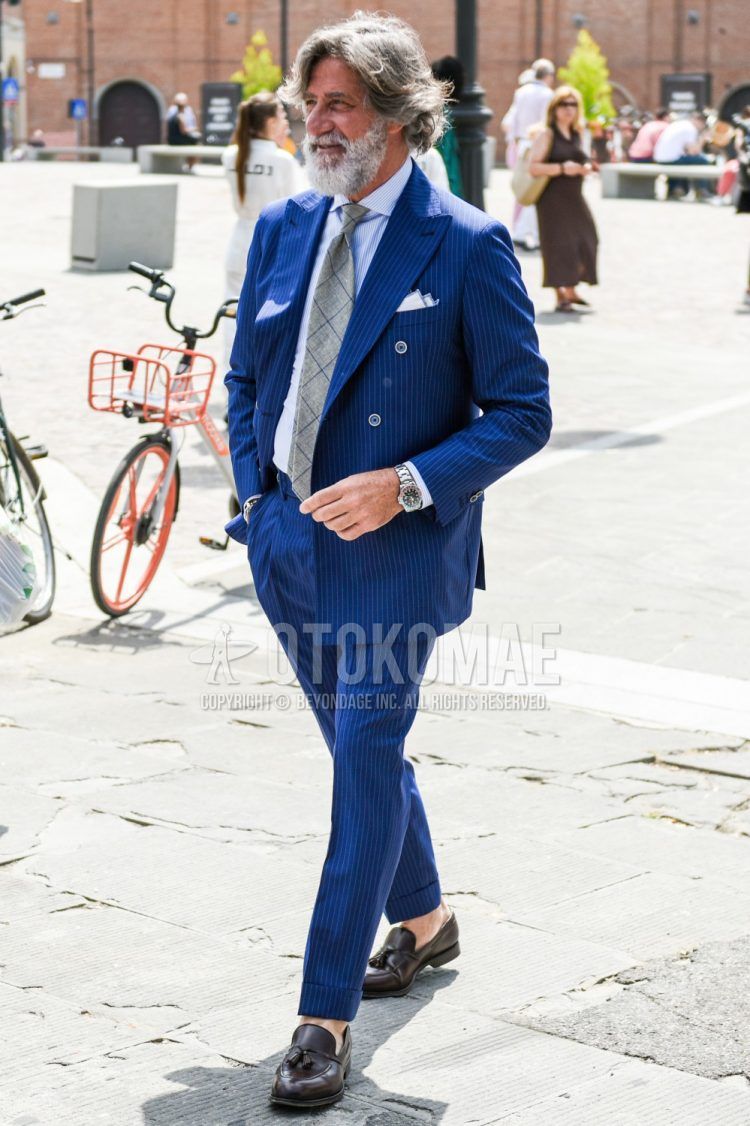 Spring and fall men's coordinate outfit with light blue striped shirt, brown tassel loafer leather shoes, navy striped suit, and gray checked tie.