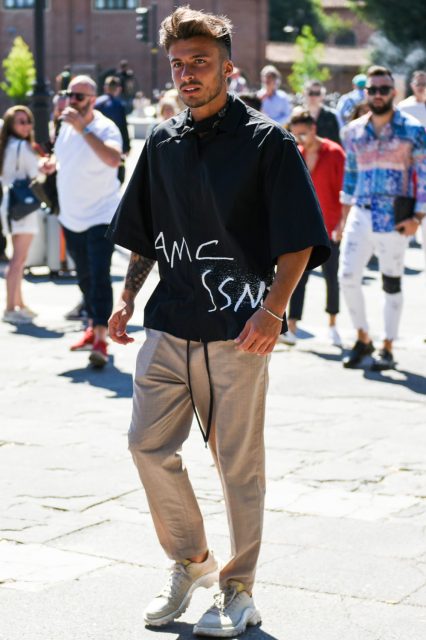 Black other bandana/neckerchief, OAMC black graphic shirt, beige check easy pants, deca logo slacks, and white low-cut sneakers for a summer men's oversized coordinate outfit.