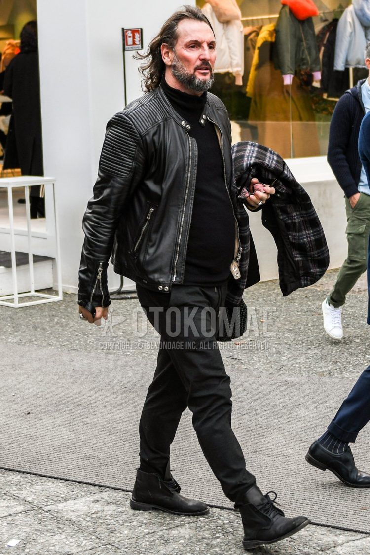 Winter men's outfit with plain black rider's jacket, plain black turtleneck knit, plain black cotton pants, and black and other boots.