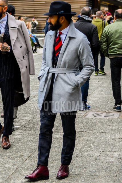 Winter men's outfit with plain black hat, plain gray belted coat, plain white shirt, red and other boots, black striped suit, and red regimental tie.
