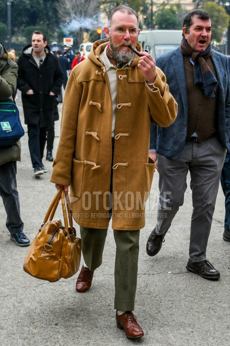 Winter men's coordinate outfit with plain glasses, plain brown duffle coat, plain white polo shirt, plain olive green ankle pants, brown wingtip leather shoes, and plain brown Boston bag.