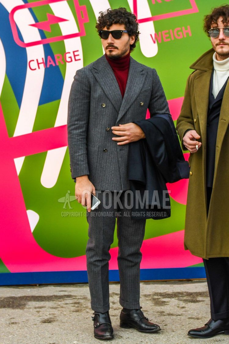 A fall men's coordinate outfit with solid color sunglasses, solid red turtleneck knit, solid black socks, black monk shoe leather shoes, and a gray striped suit.
