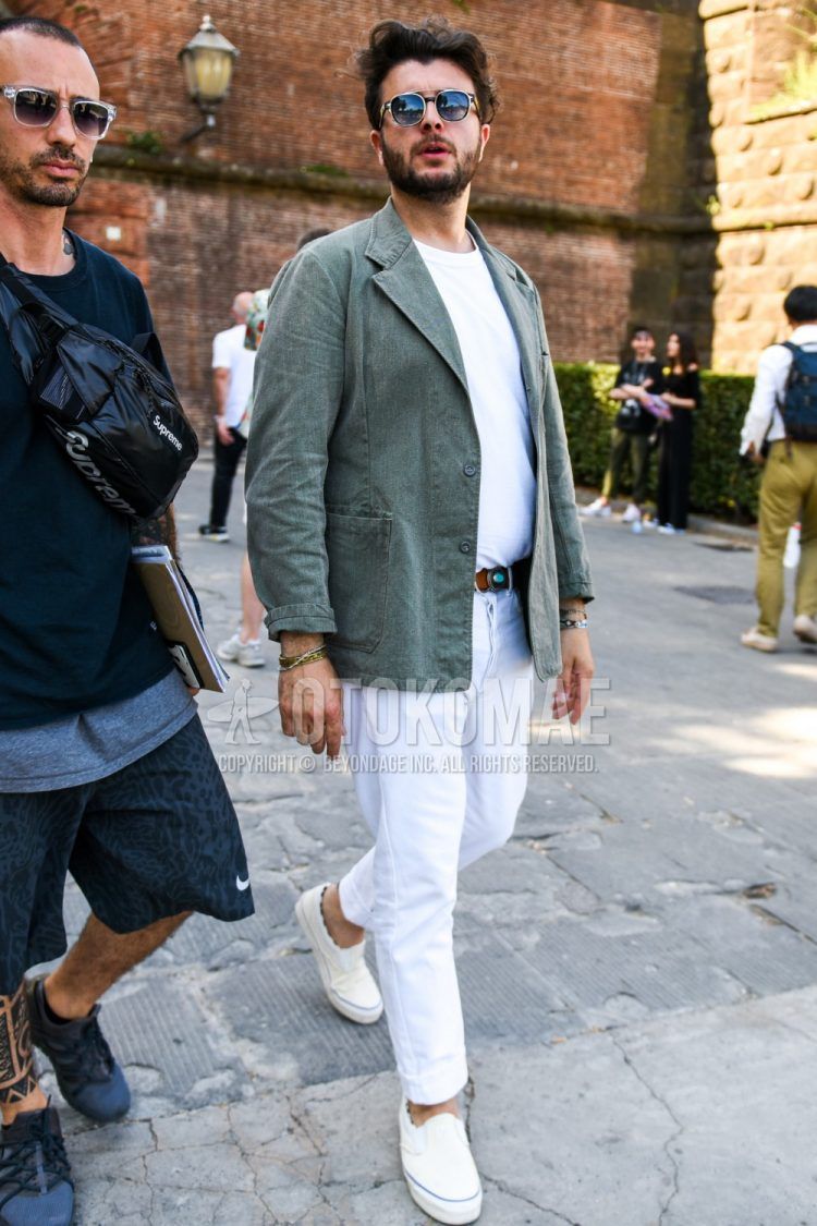 Spring, fall and summer men's coordinate outfit with plain black sunglasses, plain olive green tailored jacket, plain white t-shirt, plain brown leather belt, plain white cotton pants and white slip-on sneakers.