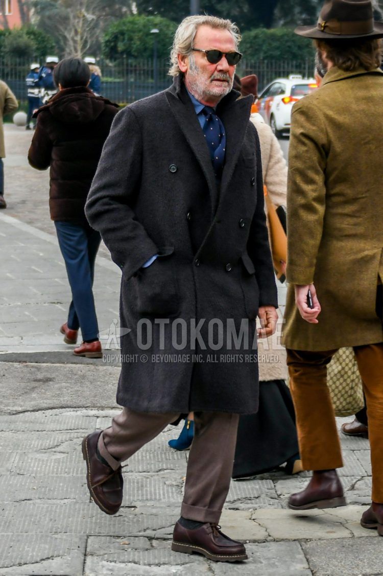 Fall and winter men's outfit with brown tortoiseshell sunglasses, dark gray solid color chester coat, blue solid color shirt, beige solid color slacks, brown U-tip leather shoes by Paraboot Mikael, and navy dot tie.