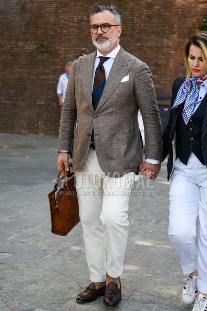 Men's coordinate and outfit with brown tortoiseshell glasses, brown outer tailored jacket, plain white shirt, plain white cotton pants, brown tassel loafer leather shoes, plain brown briefcase/handbag, brown navy regimental tie.