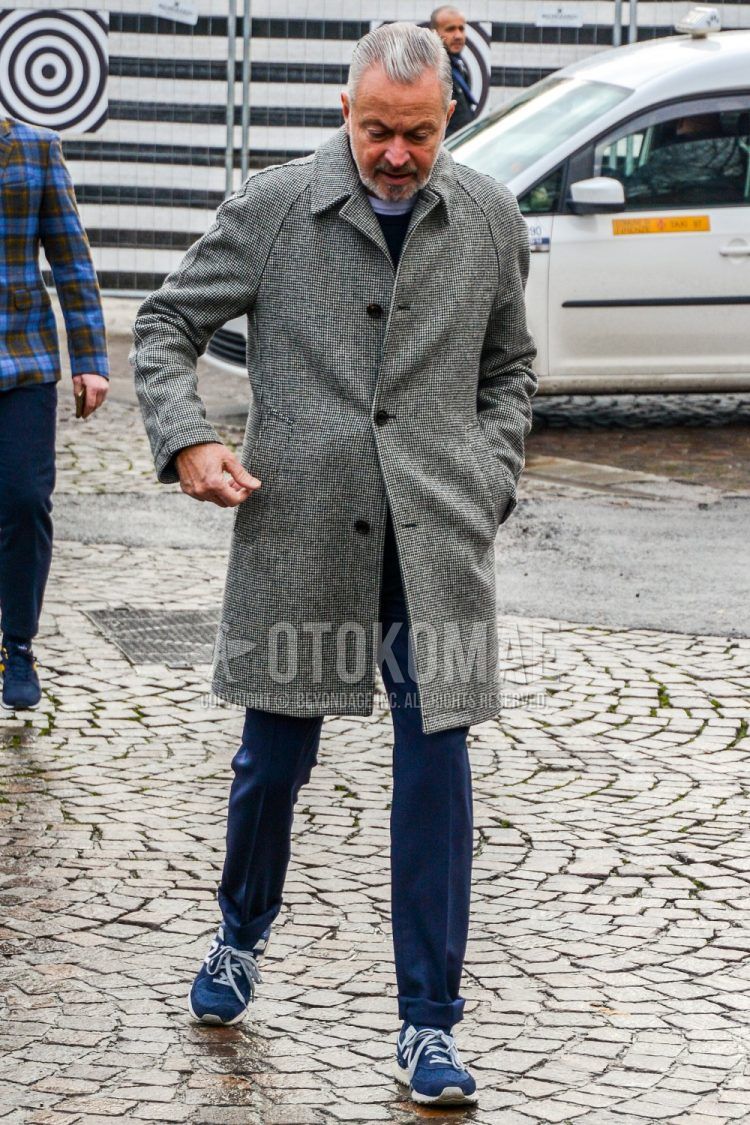 A winter men's outfit with a plain gray stainless steel collar coat, a plain navy sweater, plain navy slacks, and navy low-cut sneakers.