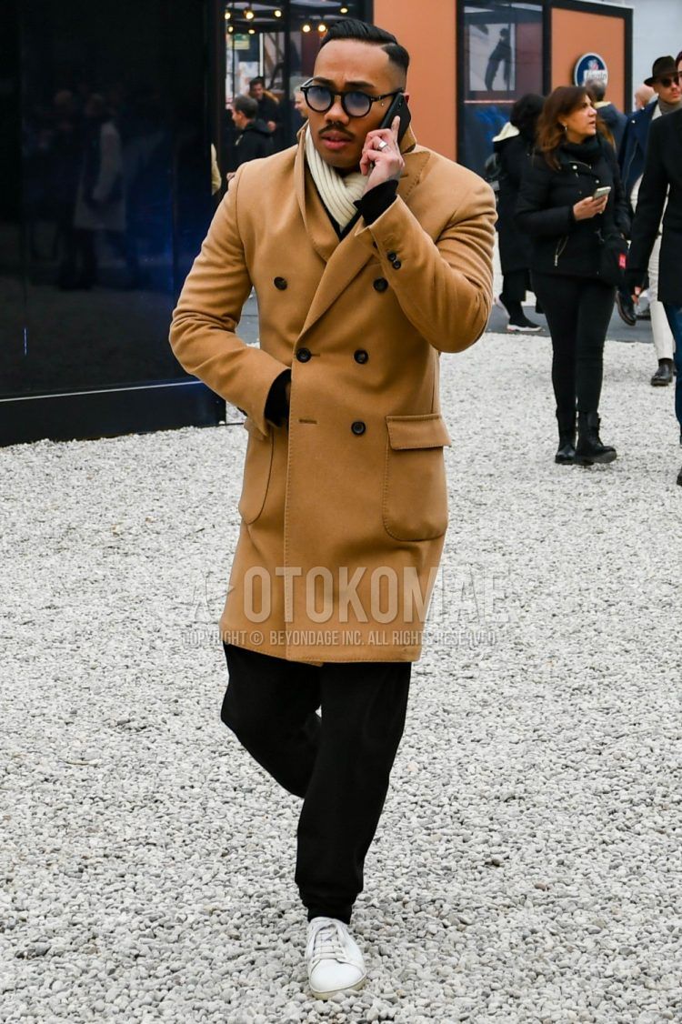 Men's fall/winter outfit with plain black sunglasses from Boston, plain beige scarf/stall, plain beige chester coat, plain black jogger pants/ribbed pants, and white low-cut sneakers.