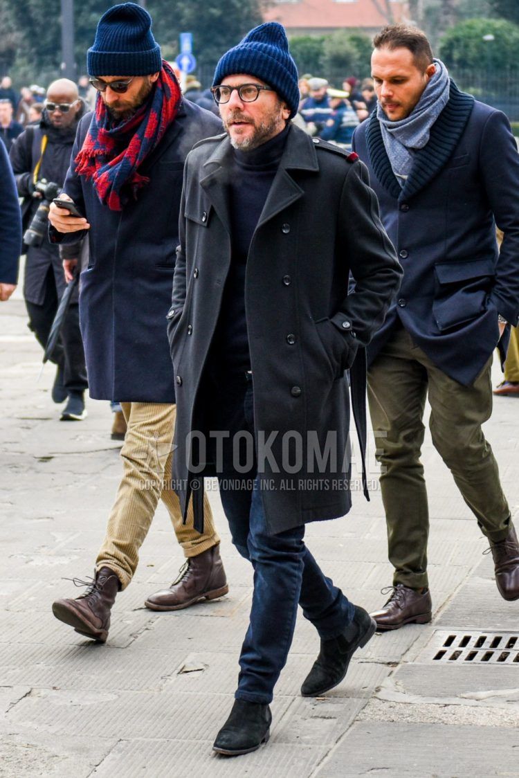 A winter men's outfit with a plain blue knit cap, plain glasses, plain black trench coat, plain navy turtleneck knit, plain navy cotton pants, and black side gore boots.