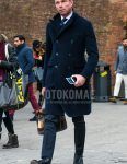 A men's fall/winter outfit with a plain navy Ulster coat, plain white shirt, plain gray slacks, black country boots, plain brown briefcase/handbag, and plain navy tie.