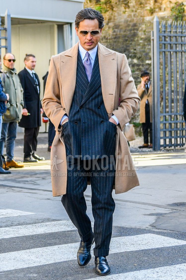 Men's fall/winter coordinate outfit with plain sunglasses, plain beige chester coat, plain white shirt, black and other loafer leather shoes, gray striped suit, purple and other tie.