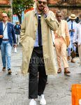 Spring and fall men's coordinate outfit with plain green sunglasses, plain beige stainless steel collar coat, blue striped shirt, plain black t-shirt, plain black chinos, plain black ankle pants, and white low-cut sneakers.