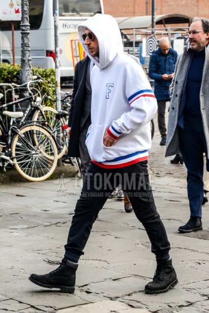 Men's coordination and outfit with plain sunglasses, white lettered hoodie, plain black jogger pants/ribbed pants, and black Timberland boots.