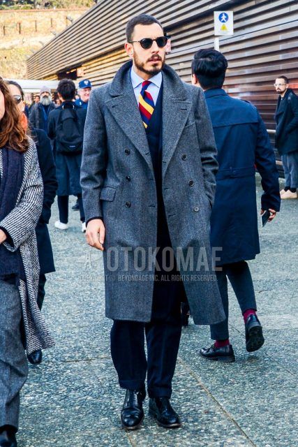 Fall and winter men's coordinate outfit with plain sunglasses, plain gray chester coat, plain light blue shirt, black other boots, plain black three-piece suit, and multi-colored regimental tie.