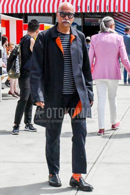 Men's coordinate and outfit with plain sunglasses, plain black stainless steel collar coat, black and white striped t-shirt, plain black ankle pants, orange socks socks, and black coin loafer leather shoes.
