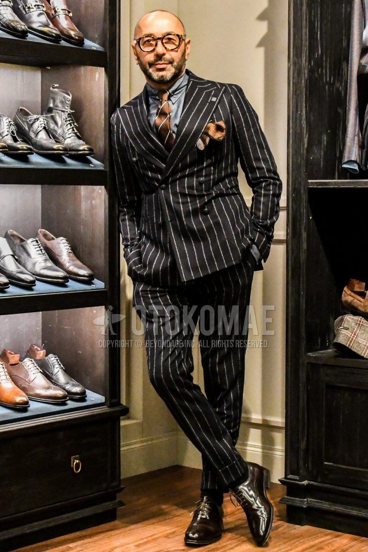 A winter/fall men's coordinate outfit with plain glasses, plain gray shirt, brown plain toe leather shoes, black striped suit, and brown regimental tie.