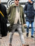 Fall/winter men's coordinate outfit with solid color knit cap, solid color sunglasses, olive green solid color stainless steel coat, beige solid color cardigan, gray solid color t-shirt, gray solid color denim/jeans, brown coin loafer leather shoes.