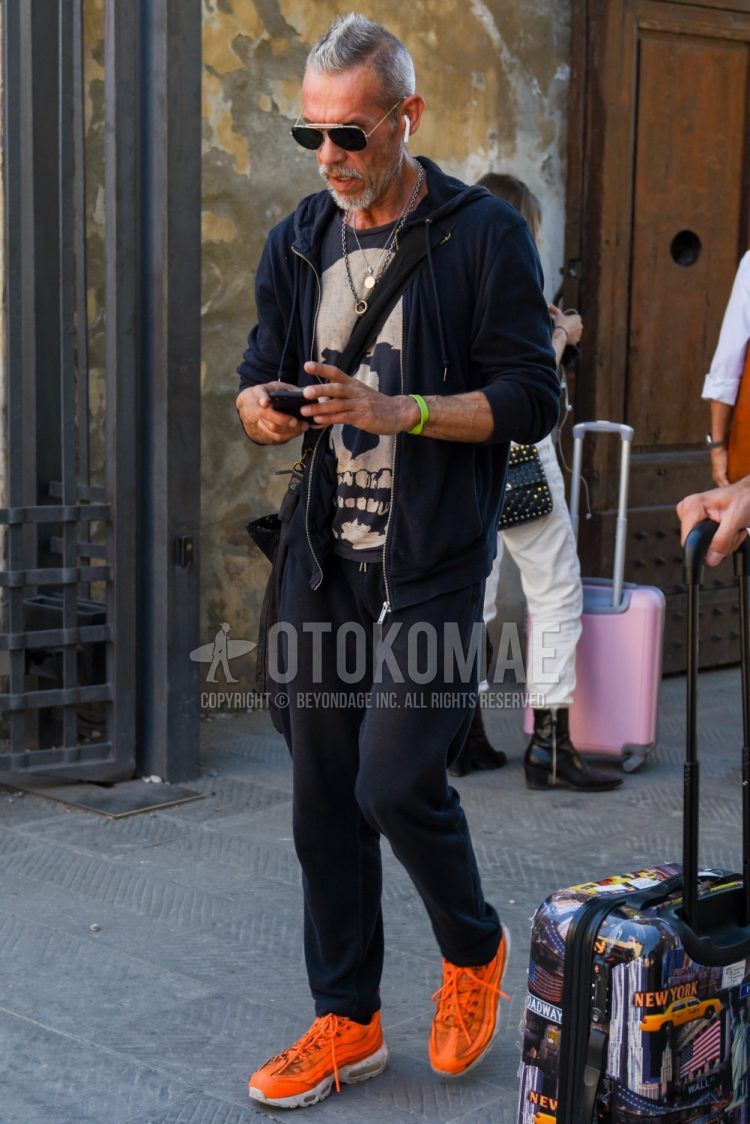 黒・シルバー無地のサングラス、黒無地のフーディ、ダークグレーグラフィックのTシャツ、黒無地のスウェットパンツ、ナイキ エアマックス95のオレンジローカットのスニーカーを合わせたメンズコーデ・着こなし。