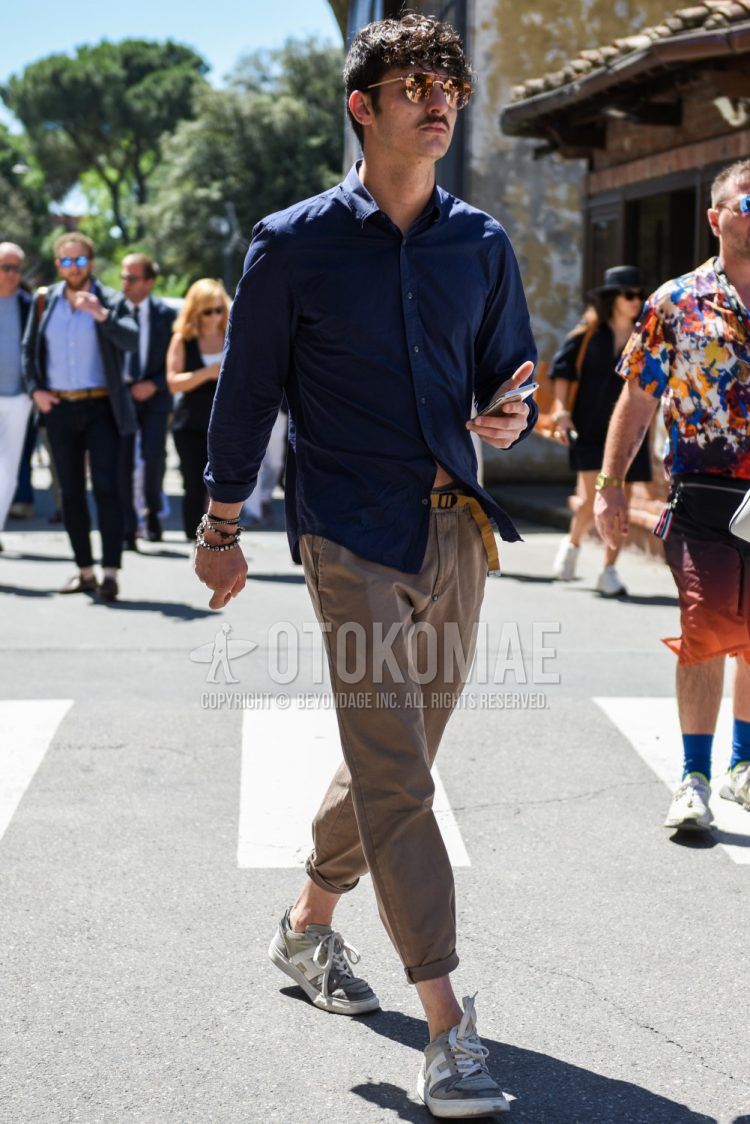 Men's coordinate and outfit with plain orange sunglasses, plain navy shirt, plain beige tape belt, plain beige chinos, plain cropped pants, and Hogan's gray low-cut sneakers.