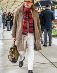 Men's fall/winter outfit with plain glasses, red other scarf/stall, brown herringbone stainless steel coat, plain beige sweater, plain white cotton pants, brown wingtip leather shoes, and plain beige backpack.