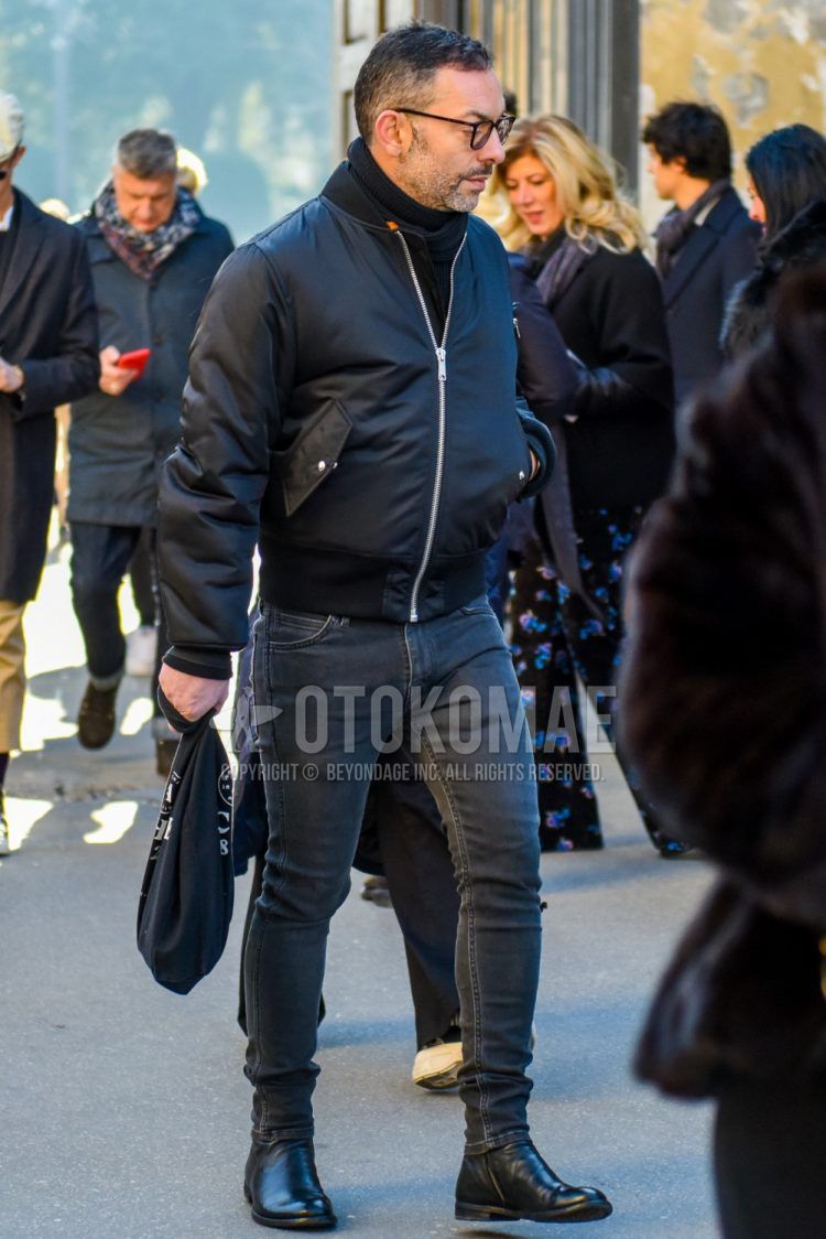 Fall/winter men's coordinate outfit with plain black glasses, plain black MA-1, plain black turtleneck knit, plain gray denim/jeans, and black other boots.