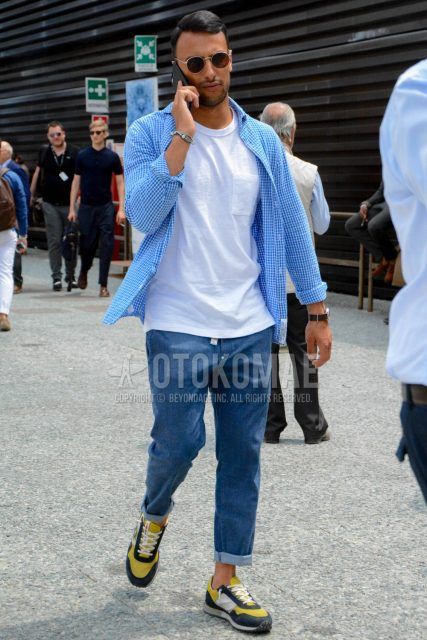 Men's coordinate and outfit with plain silver sunglasses, blue checked shirt, plain white t-shirt, plain blue denim/jeans, and black/yellow low-cut sneakers.