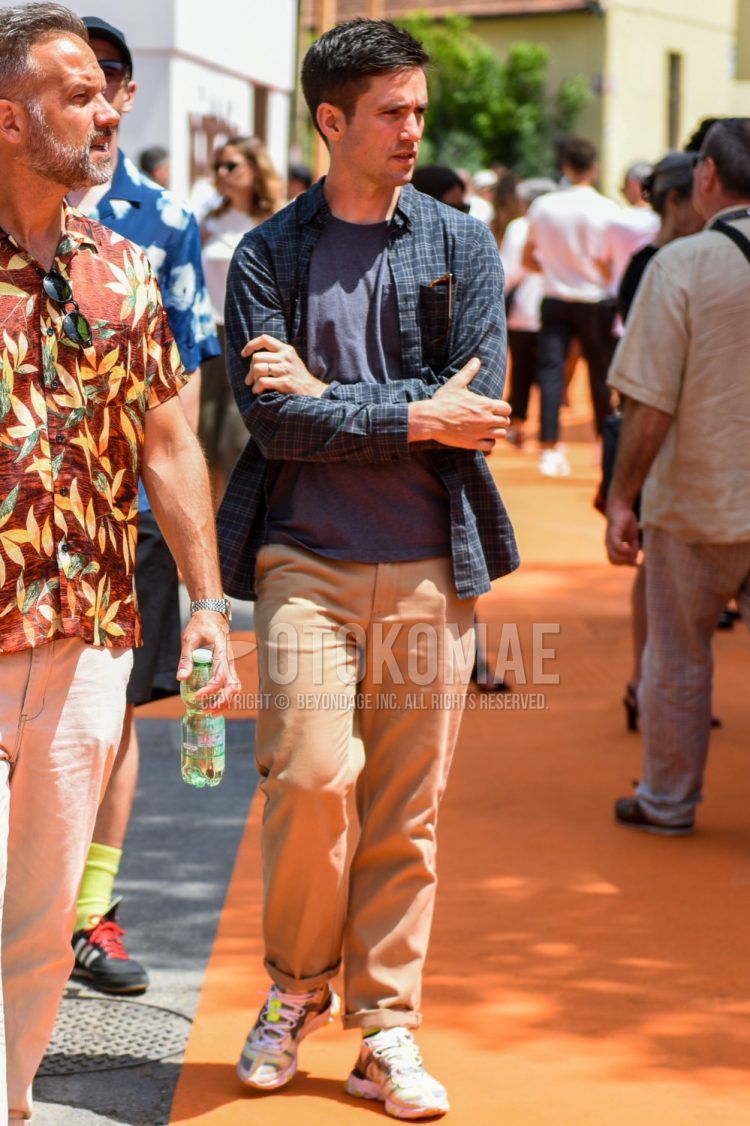 Men's coordinate and outfit with dark gray check shirt, dark gray solid color t-shirt, beige solid color cotton pants, beige solid color wide pants, and white low-cut sneakers.